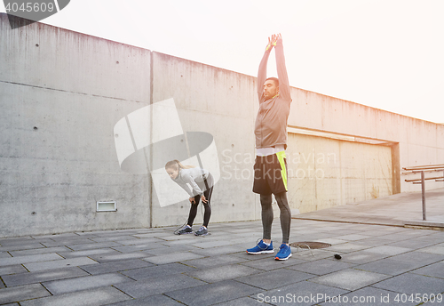 Image of tired couple stretching after exercise