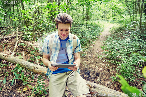 Image of happy man with backpack and tablet pc in woods