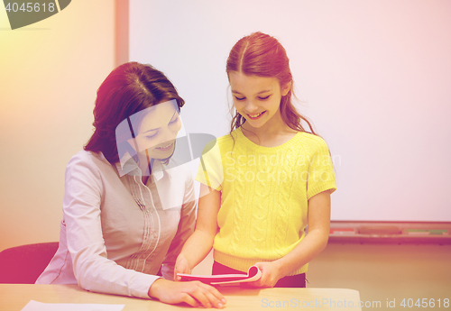 Image of school girl with notebook and teacher in classroom