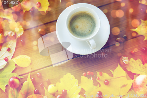 Image of close up of coffee cup on table with autumn leaves