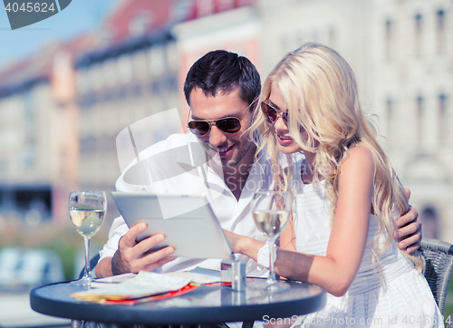 Image of couple looking at tablet pc in cafe