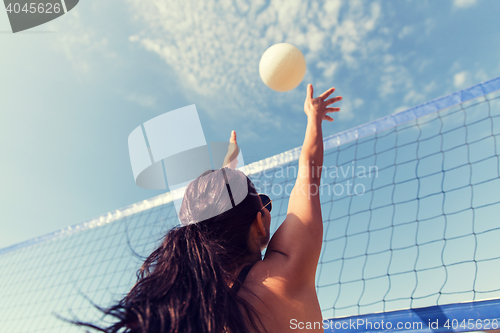 Image of young woman with ball playing volleyball on beach