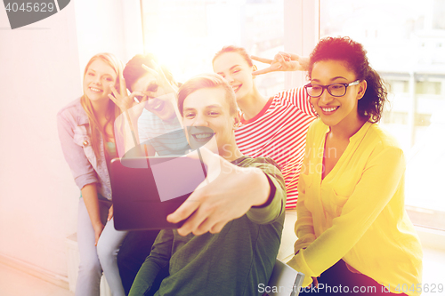 Image of smiling students making picture with tablet pc