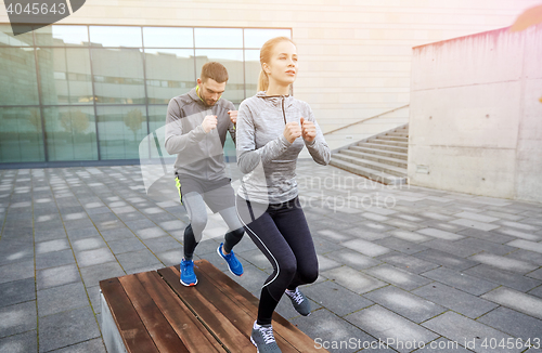 Image of couple making step exercise on city street bench