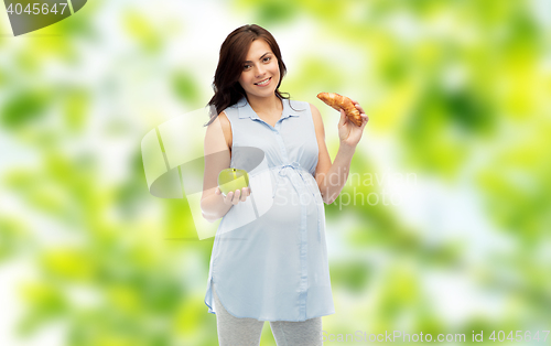 Image of happy pregnant woman with apple and croissant