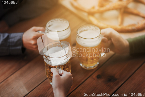 Image of close up of hands with beer mugs at bar or pub