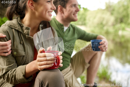 Image of happy couple with cups drinking in nature