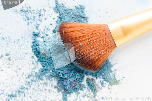 Image of Blank background with crumbly blue eye shadows and brush