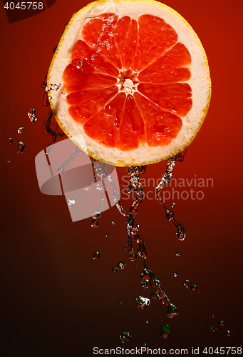 Image of Grapefruit in water splash, isolated on red background