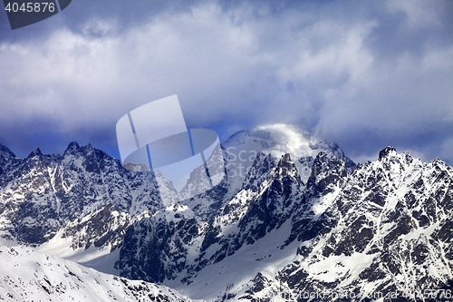 Image of Snow mountaims in clouds at sunny winter day