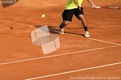 Image of Male tennis player in action on the court on a sunny day