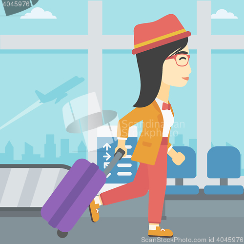 Image of Woman walking with suitcase at the airport.