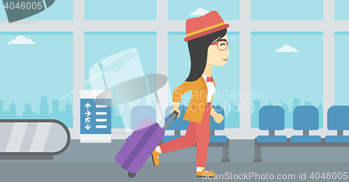 Image of Woman walking with suitcase at the airport.