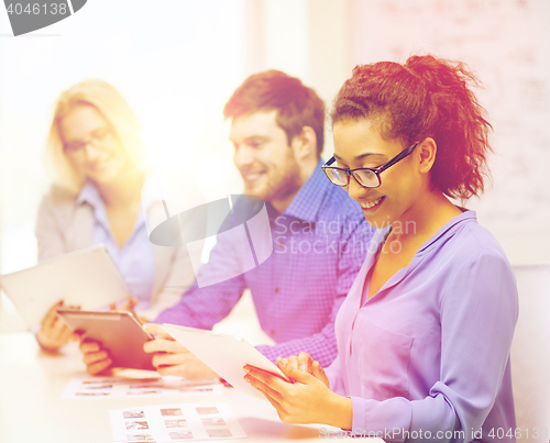 Image of smiling team with table pc and papers working