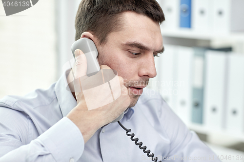 Image of face of businessman calling on phone in office