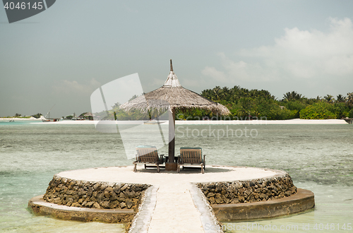 Image of palapa and sunbeds by sea on maldives beach