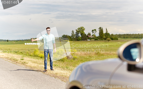 Image of man hitchhiking and stopping car at countryside