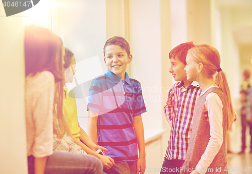 Image of group of smiling school kids talking in corridor