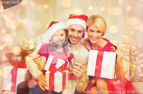 Image of smiling family holding gift boxes and sparkles