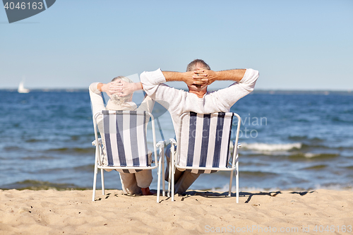 Image of senior couple sitting on chairs at summer beach