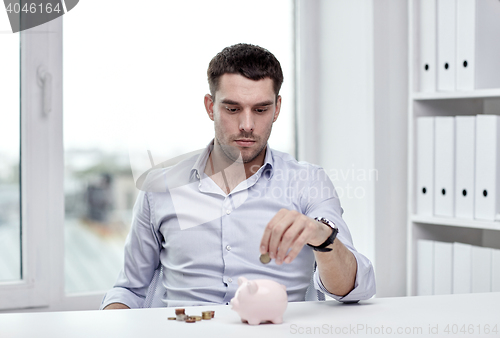 Image of businessman with piggy bank and coins at office