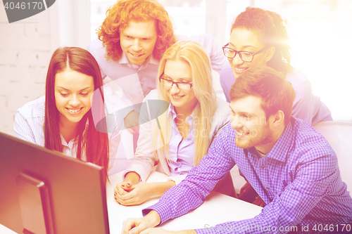 Image of smiling business team looking at computer monitor