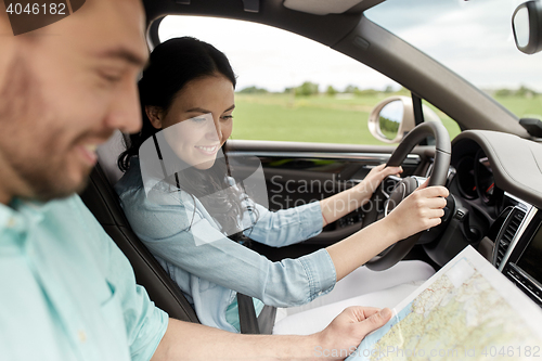 Image of happy man and woman with road map driving in car