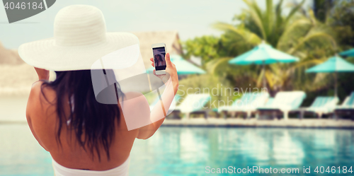 Image of smiling young woman taking selfie with smartphone