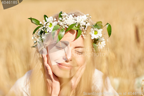 Image of happy woman in wreath of flowers on cereal field