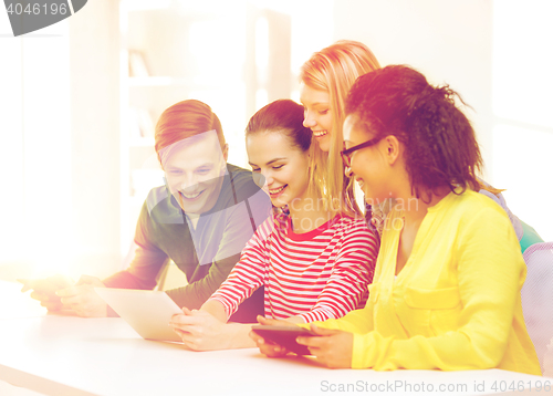 Image of smiling students looking at tablet pc at school