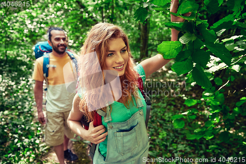 Image of happy couple with backpacks hiking in woods