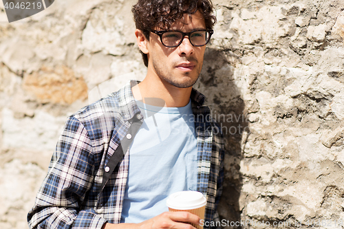 Image of man in eyeglasses drinking coffee over street wall