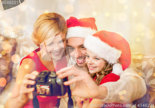 Image of smiling family in santa helper hats taking picture