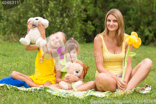 Image of Mother and daughter sitting with soft toys on a picnic