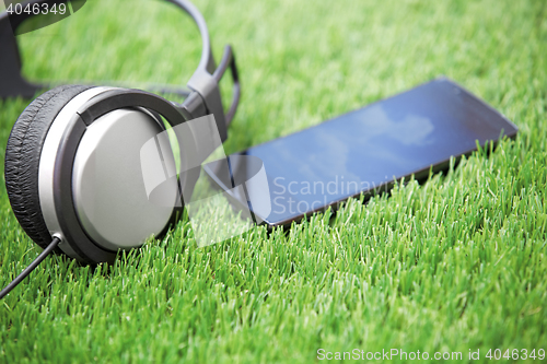 Image of Headset and smartphone laying on a grass