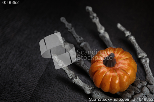 Image of Skeleton hand holding pumpkin