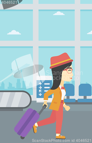 Image of Woman walking with suitcase at the airport.