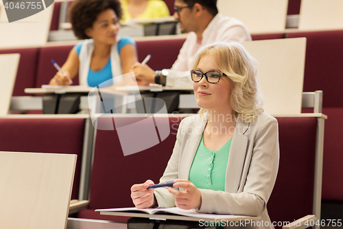 Image of student girl writing to notebook in lecture hall
