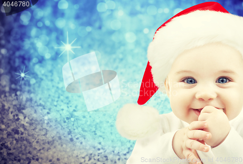 Image of happy baby in santa hat over blue holidays lights