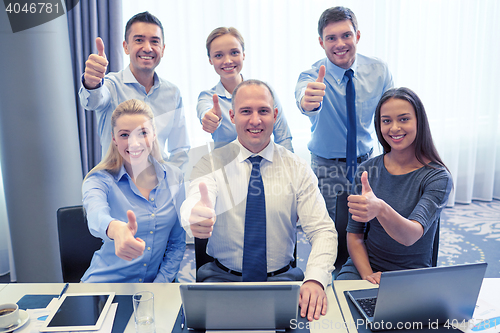 Image of business people showing thumbs up in office
