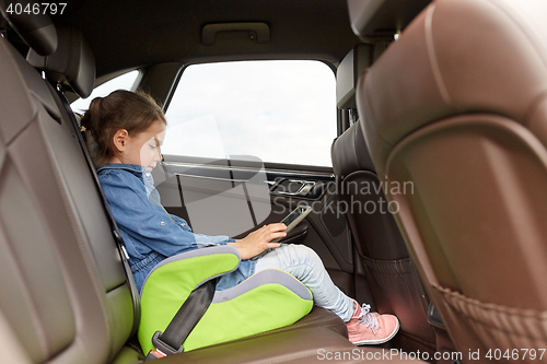 Image of happy little girl with tablet pc driving in car