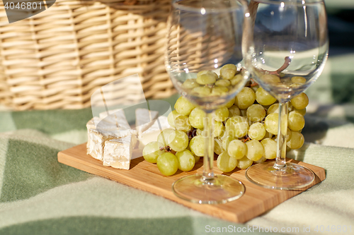 Image of picnic basket with wine glasses, grapes and cheese