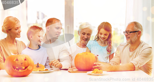 Image of happy family sitting with pumpkins at home