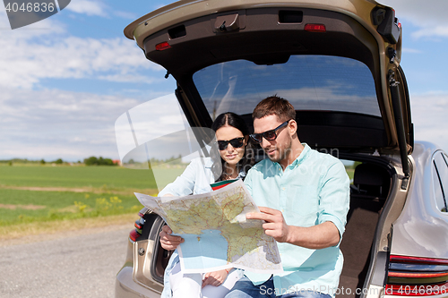 Image of happy man and woman with road map at hatchback car