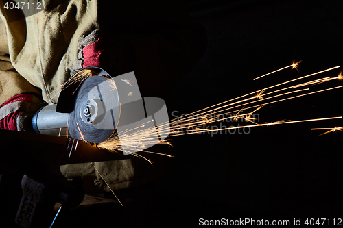 Image of Worker cutting metal with grinder. Sparks while grinding iron