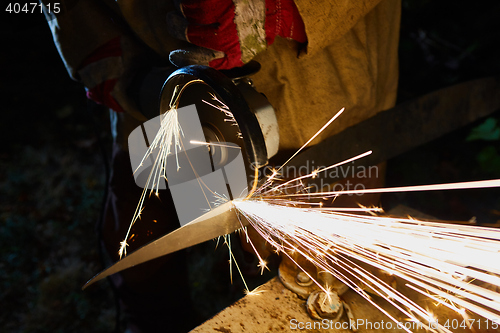 Image of Worker cutting metal with grinder. Sparks while grinding iron
