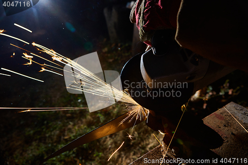 Image of Worker cutting metal with grinder. Sparks while grinding iron