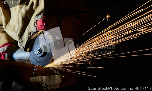 Image of Worker cutting metal with grinder. Sparks while grinding iron