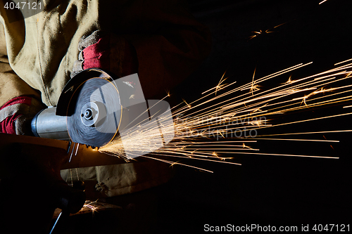 Image of Worker cutting metal with grinder. Sparks while grinding iron