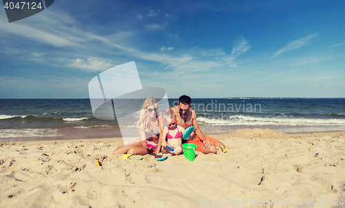 Image of happy family playing with sand toys on beach